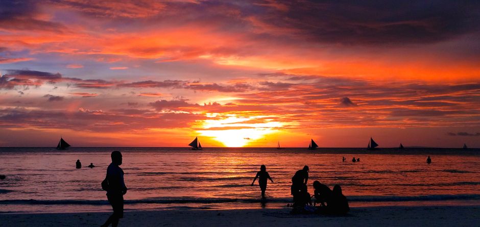 Travel insurance policy documents on a beach in the Philippines at sunset, symbolizing peace of mind