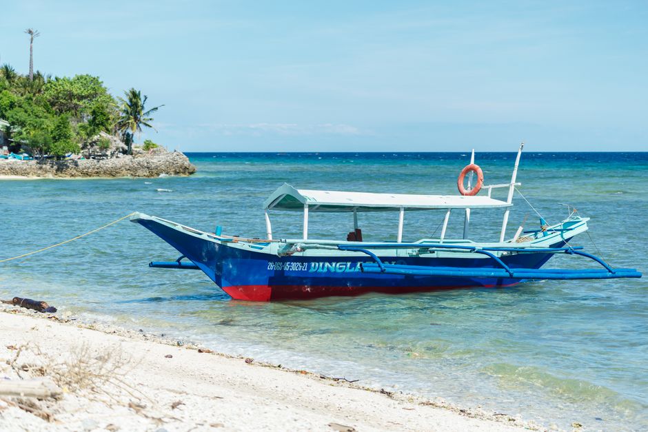 Sunny white sand beach with palm trees and clear blue water in Boracay, Philippines