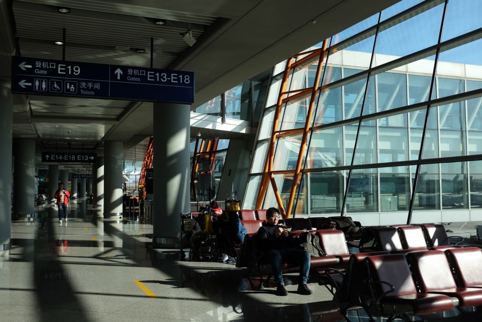 Passengers in a modern airport terminal in Taiwan, with flight information screens in the background